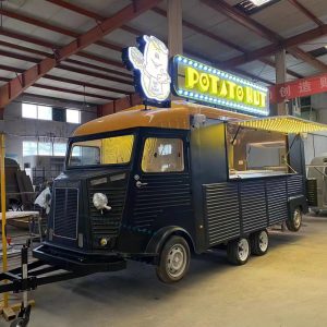 Custom 5.8m black and yellow Citroen style food trailer with double axle chassis built for a UK Potato Hut street food business.