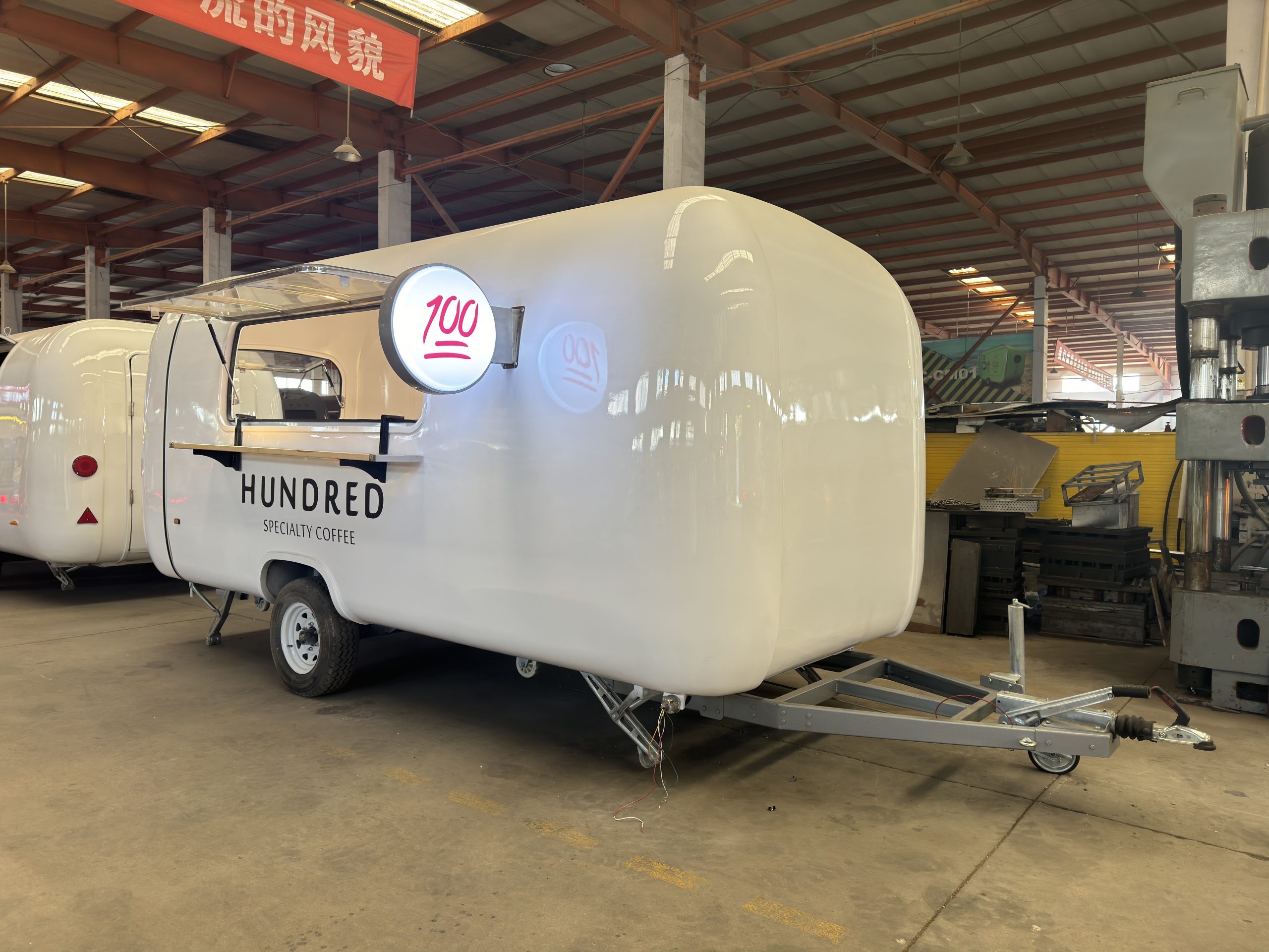 Coffee trailer serving window with illuminated round branding sign for specialty coffee business