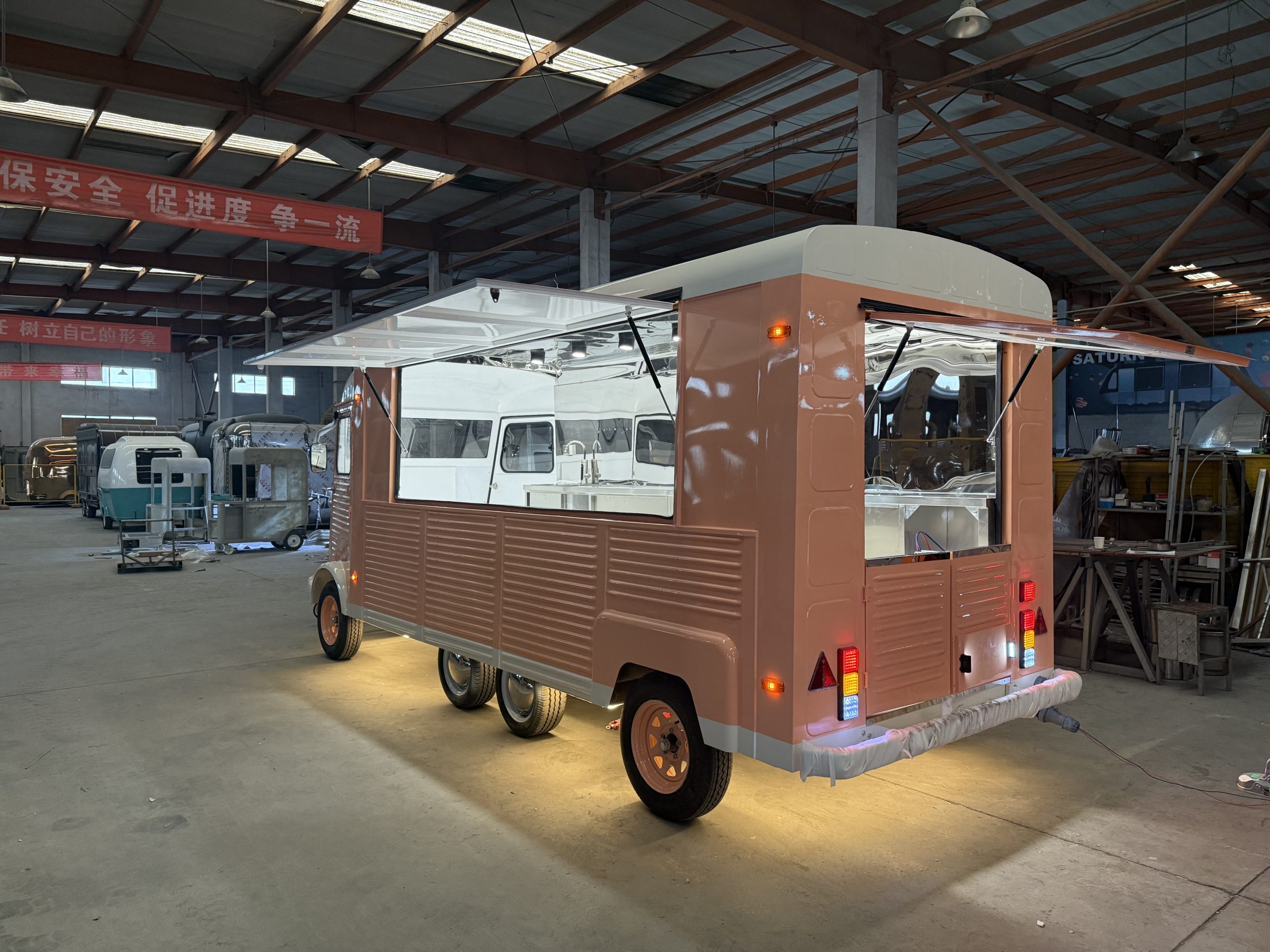 French Fries Food Truck Rear side view of opened vintage Citroën H mobile kitchen trailer, displaying interior worktops, under-counter storage, and LED chassis lighting.