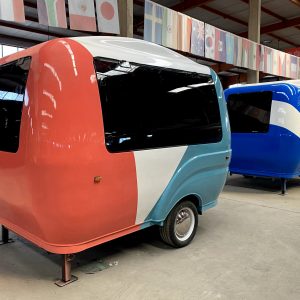BCF-10 retro fiberglass food trailer with coral pink and sky blue exterior parked inside food trailer factory