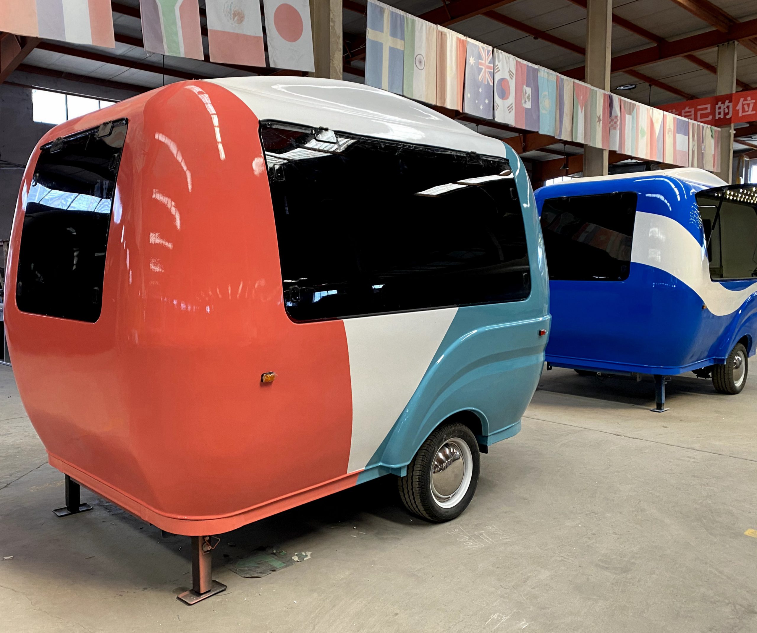 BCF-10 retro fiberglass food trailer with coral pink and sky blue exterior parked inside food trailer factory
