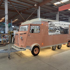French Fries Food Truck Vintage peach and cream Citroën H-style food trailer in manufacturing workshop, showing retro front face, side serving hatch, and heavy-duty wheels for the UK market.