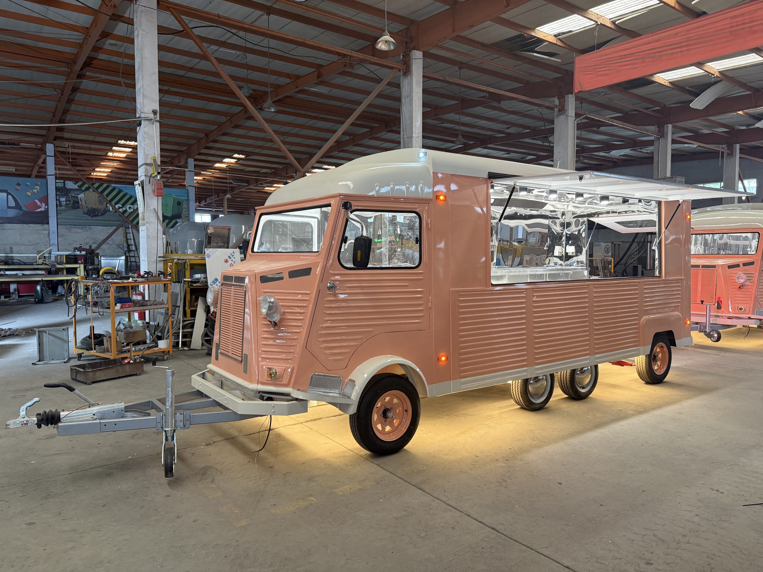 French Fries Food Truck Vintage peach and cream Citroën H-style food trailer in manufacturing workshop, showing retro front face, side serving hatch, and heavy-duty wheels for the UK market.